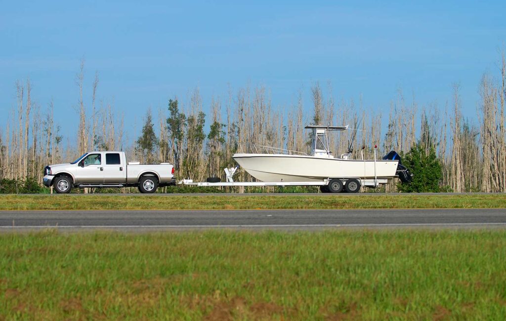 Truck pulling boat and trailer down highway